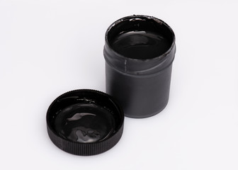 Opened black Gouache jar, on white background with copy space. Cans of different colors gouache...