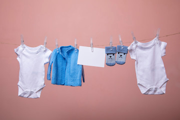 New born baby grows, jumpers, socks hanging on a clothes line against pink