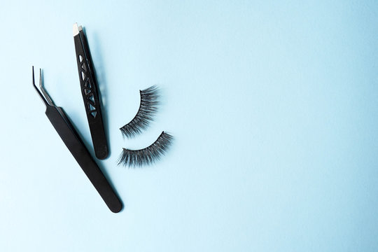 False Eye Lashes, Black Tweezers On Blue Background With Copy Space, Mockup. Instruments: Beauty And Fashion Concept - Tools For Eyelash Extension.