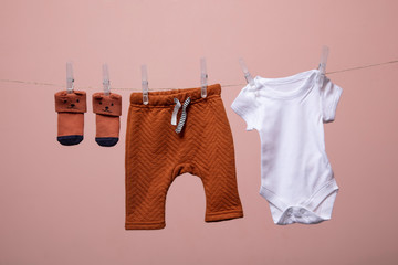 Cute baby outfit hanging from a line against a pink background