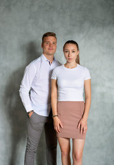 Frau und Mann , Europäisch, in Business Kleidung stehend vor grauer Wand, Studioaufnahme