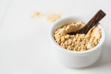 Super food maca powder in white bowl on a white background. Healthy eating concept.