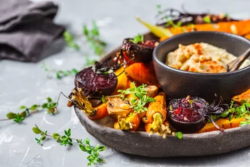  Baked vegetables with hummus in a dark dish. © vaaseenaa