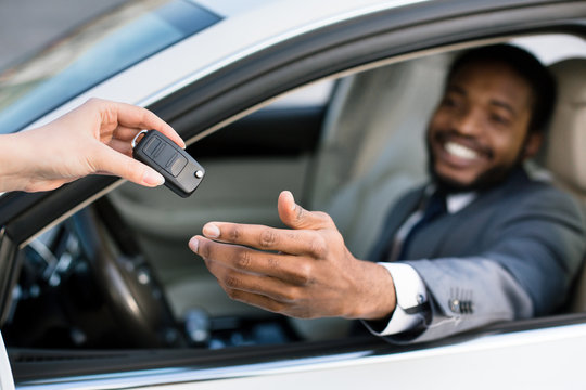Professional salesperson giving keys to new car owner