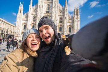 Fototapeta na wymiar Couple taking self portrait with pigeon in Duomo square in Milan. Winter traveling, Italy and relationship concept