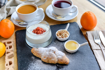 croissant with jam and sweets on black slate sprinkled with powdered sugar