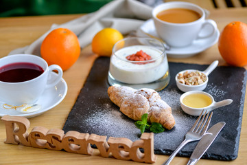 croissant with jam and sweets on black slate sprinkled with powdered sugar