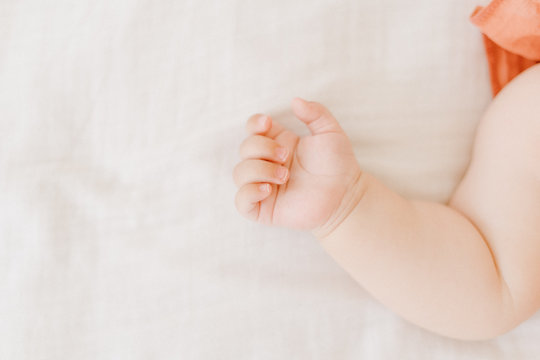 Tiny New Born Caucasian Baby Arm Partial View. Closeup Picture of Small Kid Open Hand. Palm with Cute Fingers Looking Up. Little Innocent Child Lying on Light Soft Blanket Background