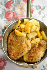 Polish breaded pork cutlet with potatoes on pan