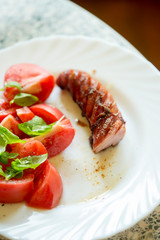 Grilled sausage with tomato and basil salad 