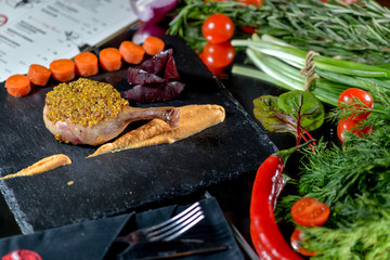 chicken leg in a beautiful server on a black slate in a restaurant on the table