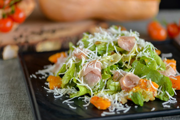 jamon and pumpkin salad on a square black plate