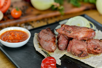 kebab on pita bread served on a black slate in a restaurant