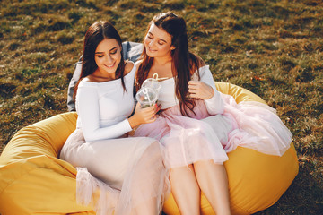 Beautiful girls sitting in a park. Friends have fun in a summer city