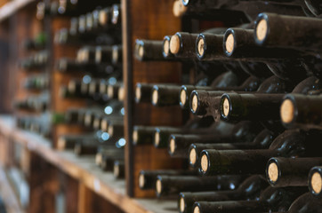 dusty wine bottles on a wooden shelf in a wine cellar