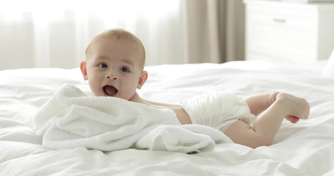 Adorable little child with towel after bathing on bed at home