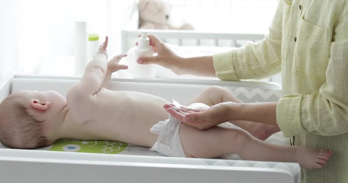 Mother taking care of her little child on changing table