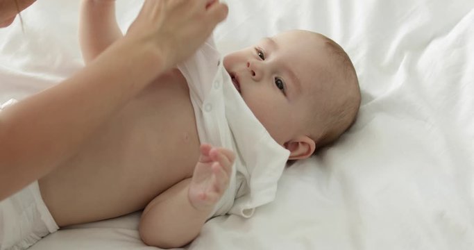 Mother taking off her little child's clothes at home, closeup
