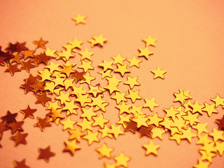 Golden stars glitter on orange paper background