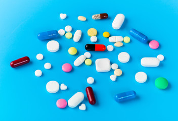 Medicine pills, tablets and capsules over blue background