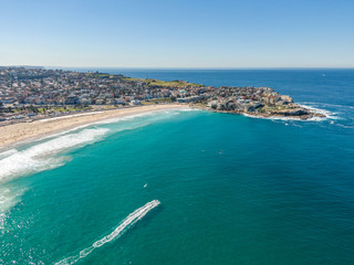 Beautiful aerial high angle drone view of the suburbs of Bondi Beach and North Bondi, one of the most famous beaches in Sydney, New South Wales, Australia. Motor boat driving through the ocean.