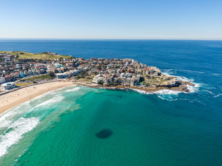 Beautiful aerial high angle drone view of the suburbs of Bondi Beach and North Bondi, one of the most famous beaches in Sydney, New South Wales, Australia. Large shoal of fish visible in the ocean.