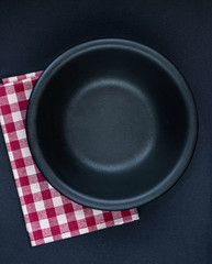 Black plate, cutlery and red checkered napkin on a black  table top view. Table setting. Flat lay.