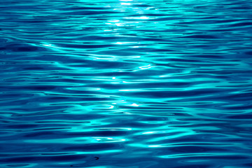Vibrant aqua blue colored sea ripples with sunlight reflections