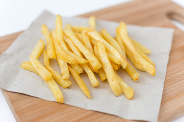 French fried potatoes on cutting board top view. Tasty french fries, fast food menu.