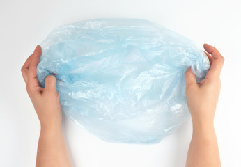 blue plastic garbage bag in female hands on a white background