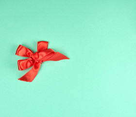 knotted bow of red silk ribbon on a green background
