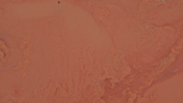 Terracotta, red ochre, red clay, orange. Paints mix in motion. Decorative brilliant liquid texture. Paint movement and mixing
