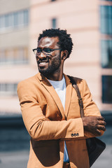 handsome, stylish african american businessman in glasses looking away while standing on rooftop