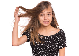 Obraz premium Hair care. Close up portrait of frustrated teen girl with messed hair, isolated on white background. Beautiful sad child with disheveled hair on head. Upset female young model holding her hair.