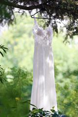 white wedding dress hanging on the tree