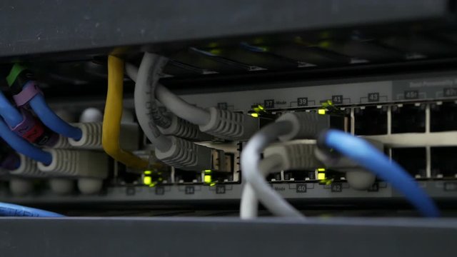 Blinking network ethernet active switch with connected cables in server room.