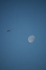 Aeroplane and the moon in a blue sky background