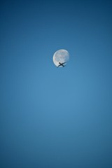 Aeroplane and the moon in a blue sky background