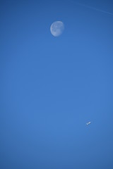 Aeroplane and the moon in a blue sky background