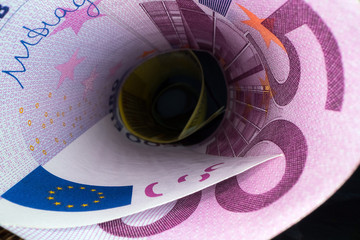 Inside the money tunnel. Abstract perspective view of euro back notes rolled in a tube. Saving and...