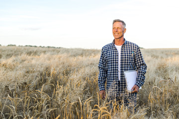 Naklejka na ściany i meble Smiley man standing in a wheat field