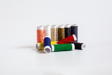  Threads of different colors with the coils in a row and swing needle on white background