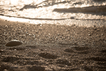 Background of stones on the shore. Close up in the blurry sunset light in the distance.