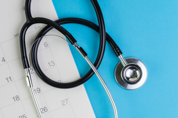 Health care and medical exam schedule calendar, reminder or appointment concept, doctor's stethoscope on white clean calendar with date on blue background with copy space