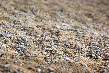 Background of stones on the shore. Close up in the blurry sunset light in the distance.