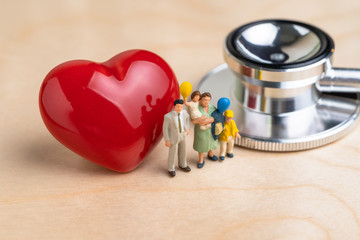 Miniature people lovely family parent and children with doctor's stethoscope and shinny red heart...