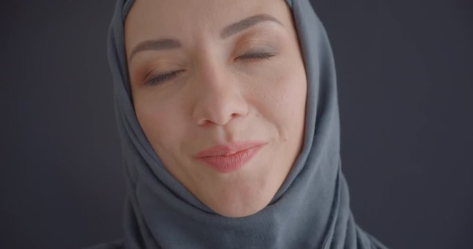 Closeup portrait of young attractive muslim woman in hijab looking at camera smiling cheerfully with background isolated on gray