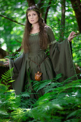 Elf woman in a green dress in the forest