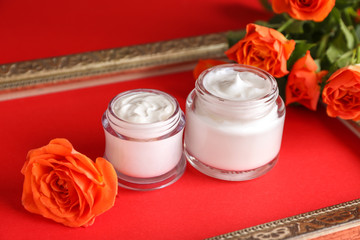 Body cream with rose flowers on color background