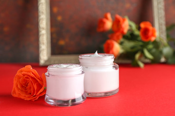 Body cream with rose flower on color table